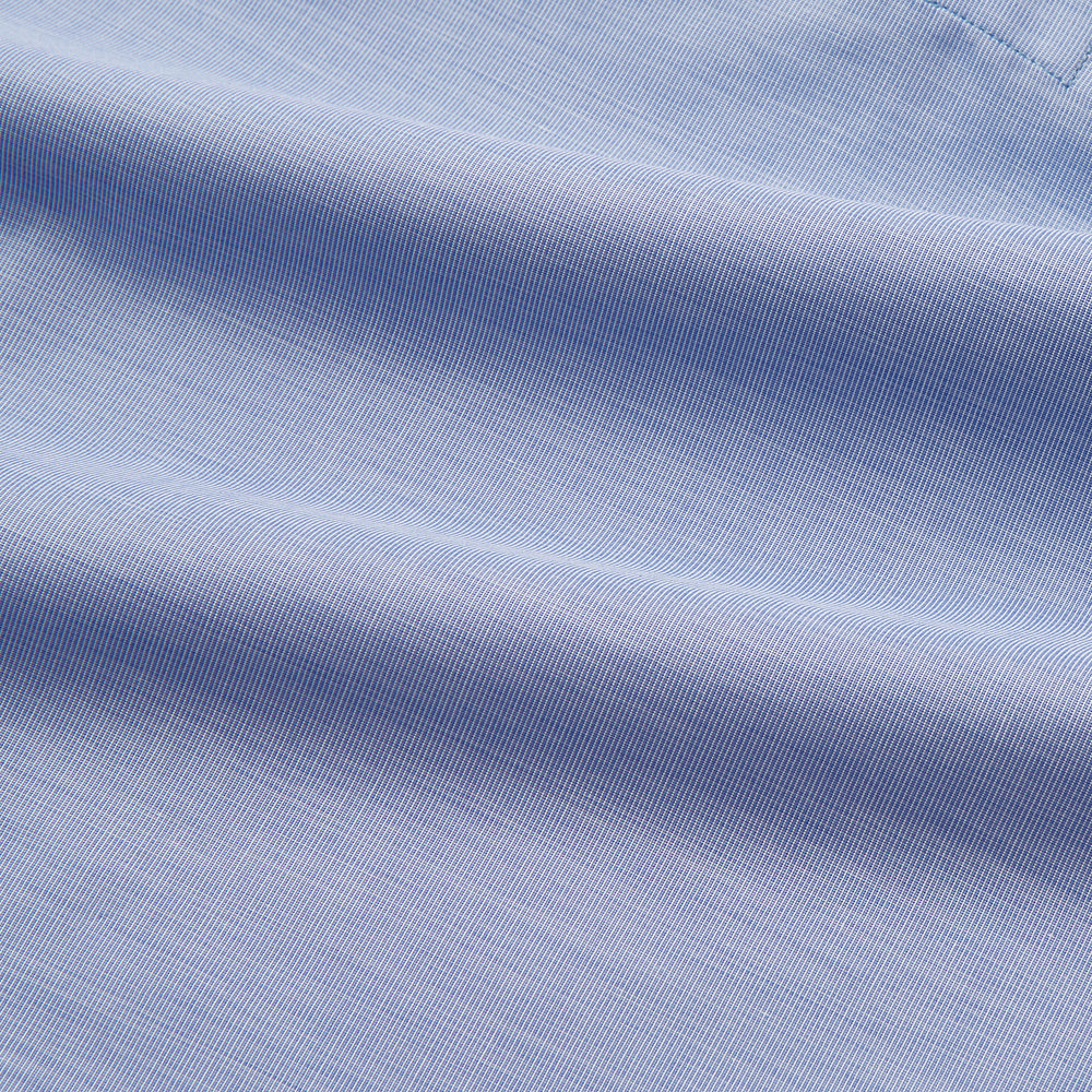 The Blue Piped End-on-End Cotton Nightshirt by Turnbull & Asser features light blue cotton, red piped accents, a chest pocket, high-low hem, and half-button placket—luxurious nightwear inspired by classic nightshirt style.