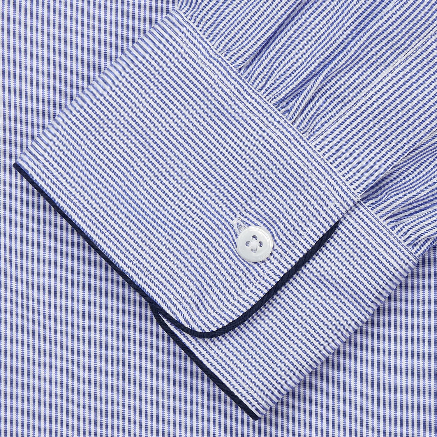 View 3 of product The Turnbull & Asser Blue Fine Bengal Stripe Piped Cotton Nightshirt features long sleeves, a chest pocket, black collar piping, curved hem, and side slits. It is displayed laid flat on a white background.