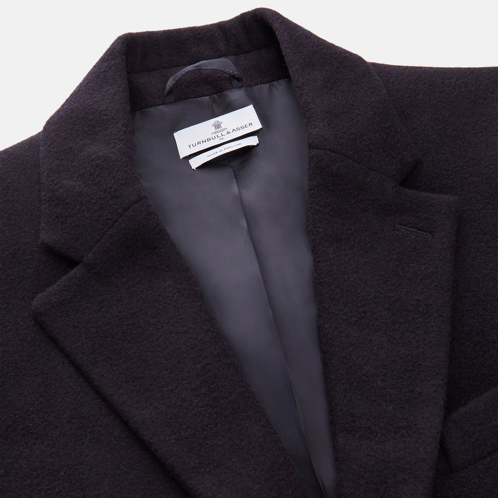 The Turnbull & Asser Navy Cashmere Joseph Overcoat features notched lapels, three front pockets, buttoned cuffs, and a hidden button closure—an essential men’s outerwear piece shown against a plain white background.