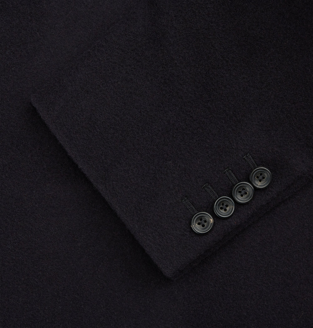 The Turnbull & Asser Navy Cashmere Joseph Overcoat features notched lapels, three front pockets, buttoned cuffs, and a hidden button closure—an essential men’s outerwear piece shown against a plain white background.