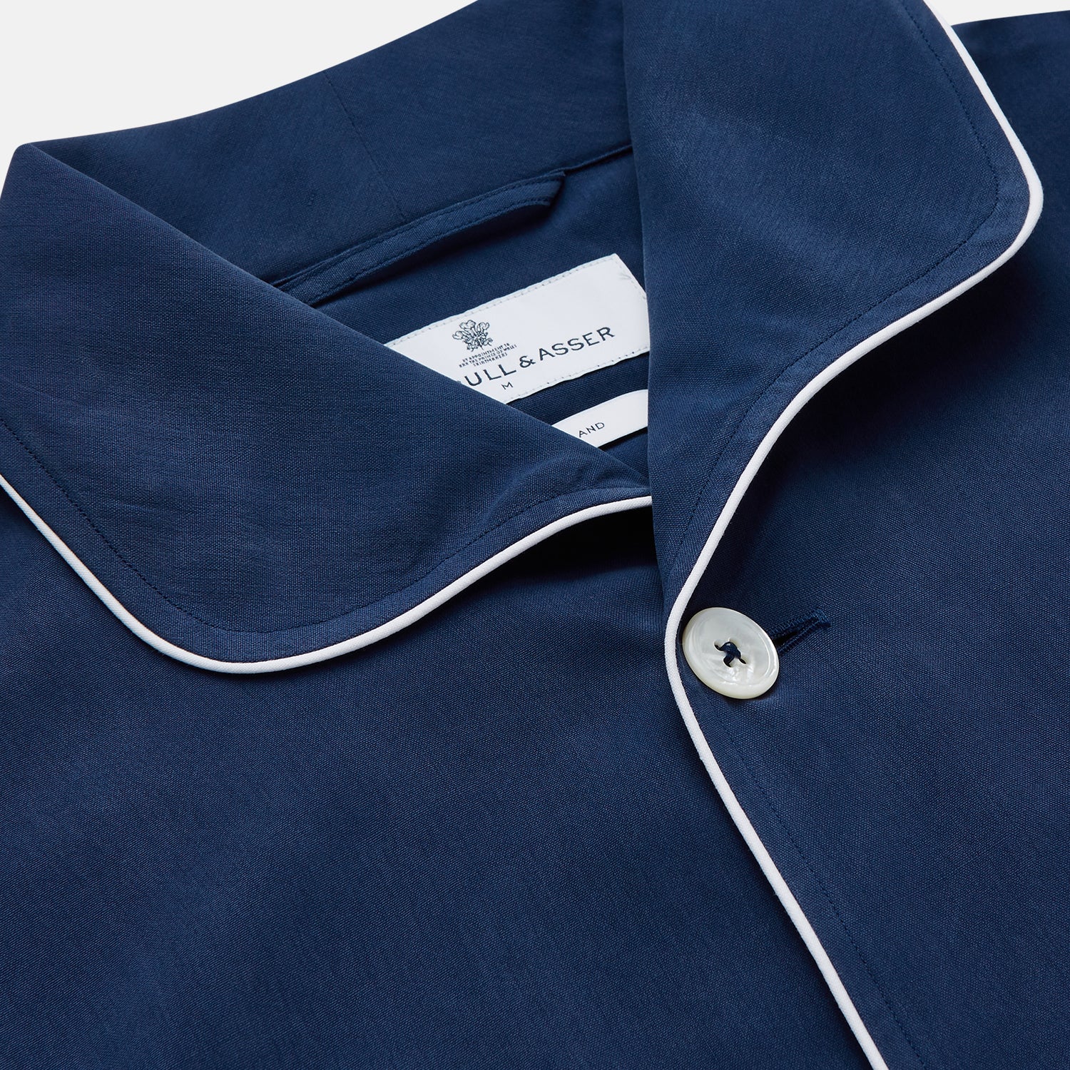 View 3 of product The Turnbull & Asser Navy Piped Silk Pyjama Set features a long-sleeve button-up top with a chest pocket and matching drawstring pants, laid flat on a white background for a luxurious look.