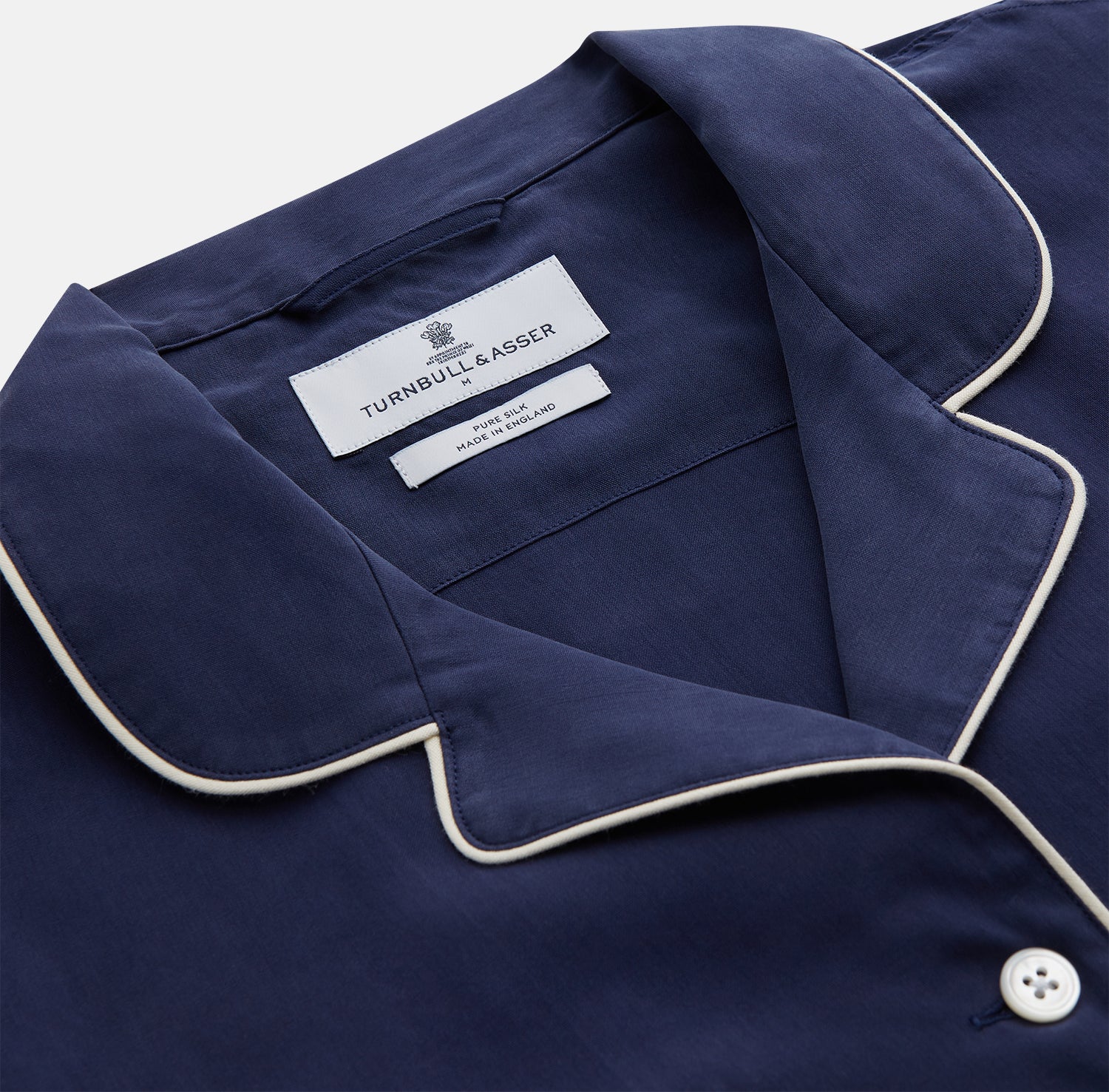 View 3 of product The Women's Harriet Navy Silk Pyjama Set by Turnbull & Asser features a long-sleeve, button-up top with white piping and chest pocket, plus matching drawstring pants—luxurious sleepwear displayed on a white background.