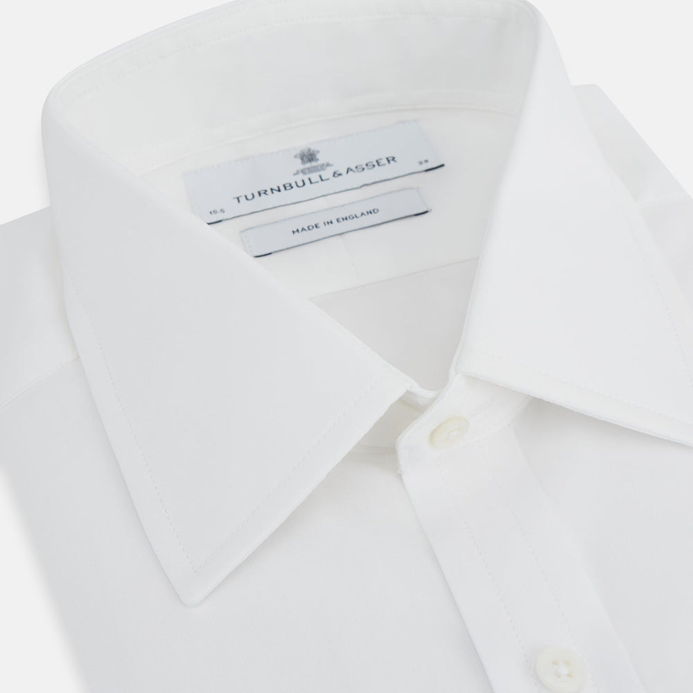 The Turnbull & Asser Plain White Cotton Shirt features a T&A collar, double cuffs, and a straight hem—ideal for minimalist style. Displayed on a plain white background.