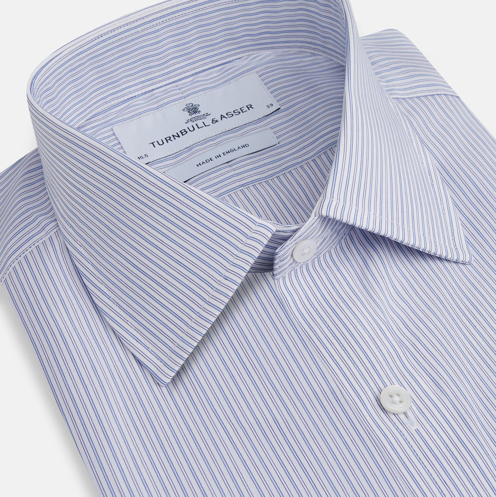 The Light Blue Track Stripe Mayfair Shirt by Turnbull & Asser is a long-sleeve button-up with thin white stripes, pointed collar, and buttoned cuffs. Expertly crafted from Egyptian cotton, it's shown laid flat on a white background.
