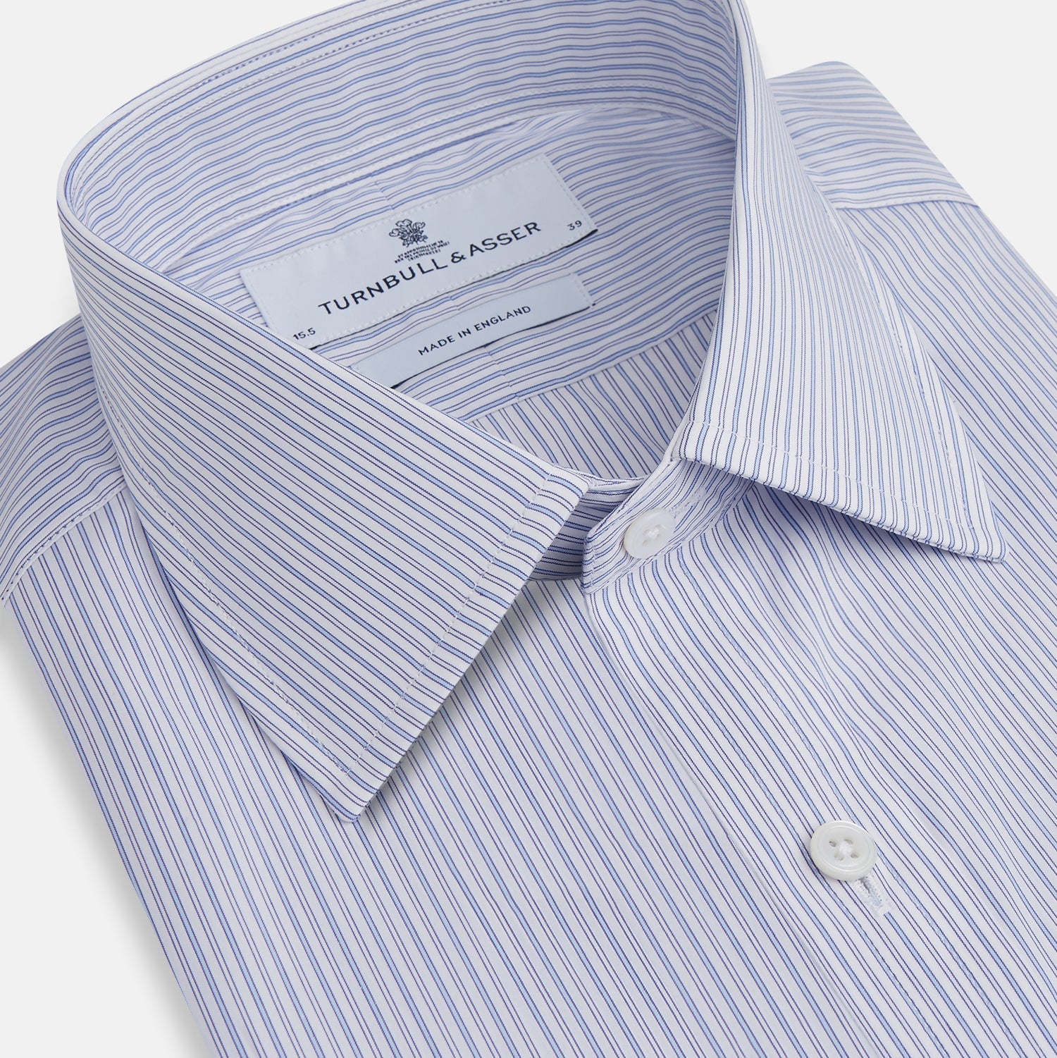 View 2 of product The Light Blue Track Stripe Mayfair Shirt by Turnbull & Asser is a long-sleeve button-up with thin white stripes, pointed collar, and buttoned cuffs. Expertly crafted from Egyptian cotton, it's shown laid flat on a white background.