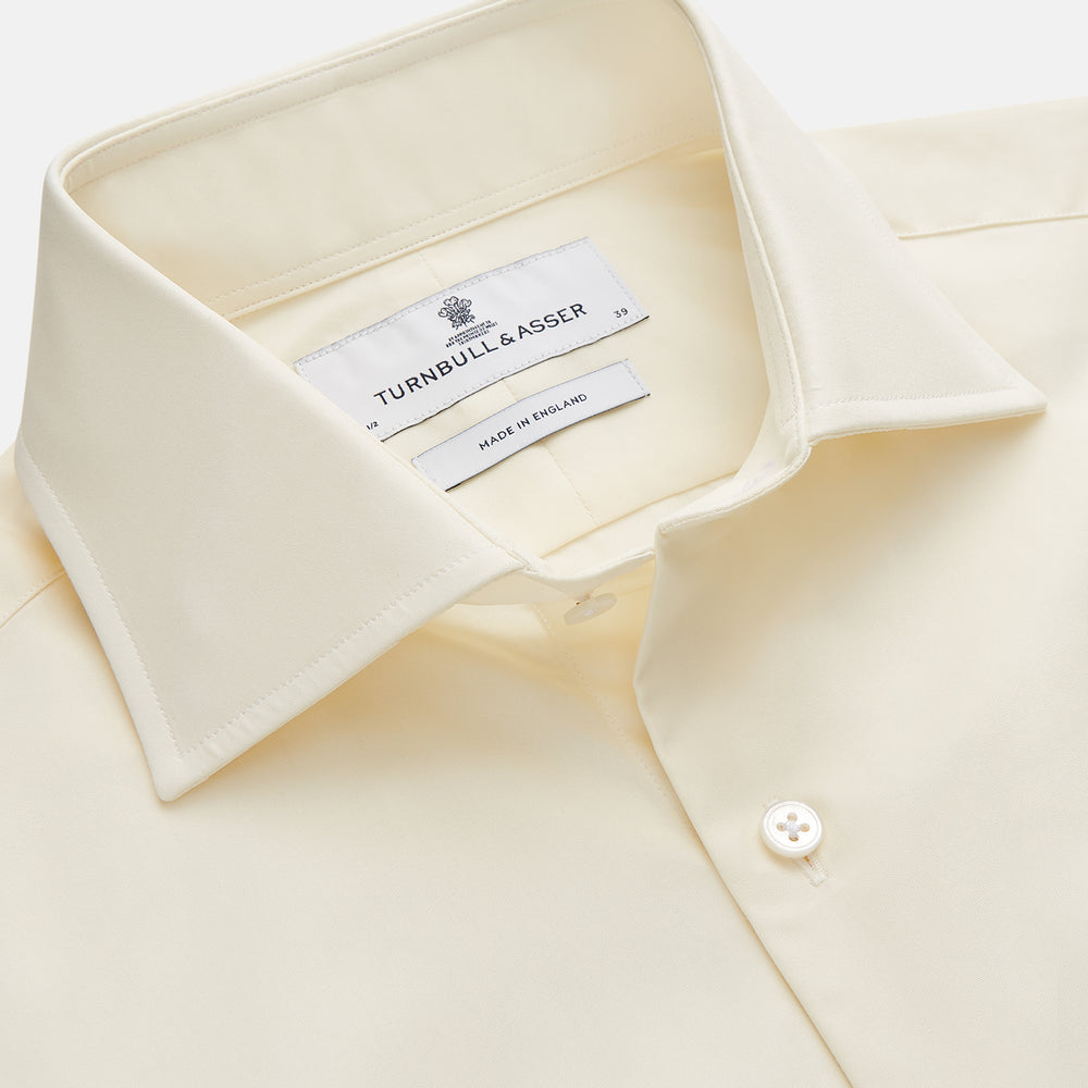The Turnbull & Asser Tailored Fit Cream Cotton Shirt features a Kent collar and double cuffs, shown laid flat against a white background—ideal for pairing with statement ties.
