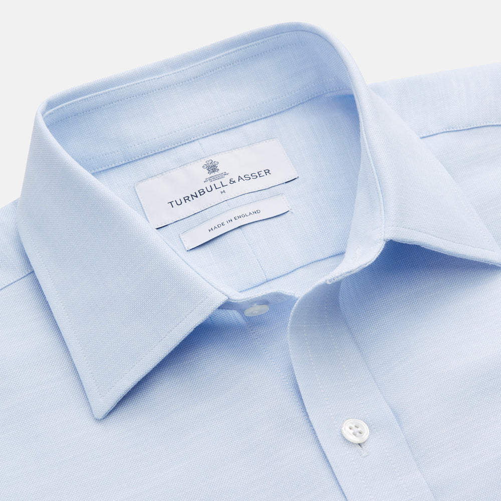 The Turnbull & Asser Plain Blue Weekend Fit Chambray Finch Shirt features a Derby collar, long sleeves, and a front chest pocket—shown laid flat on white—ideal for casual weekend wear.
