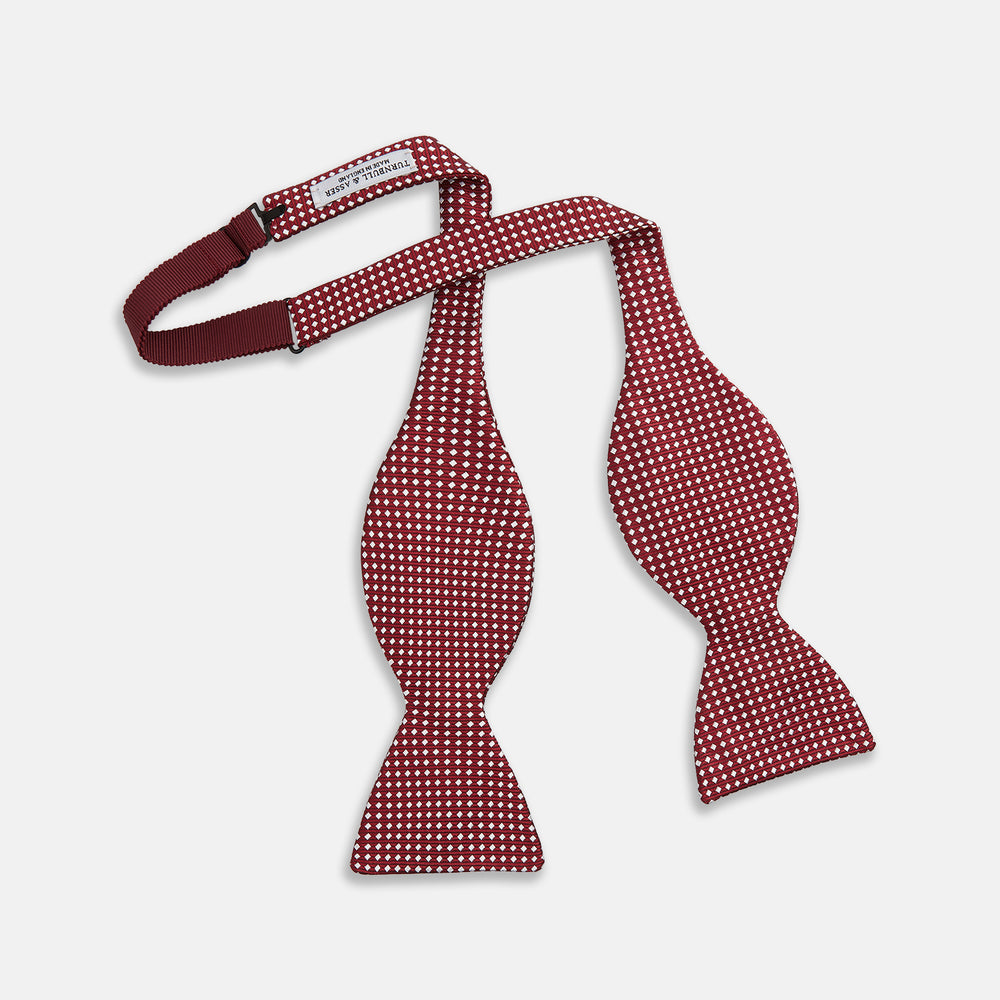 The Turnbull & Asser Burgundy and White Diamond Silk Bow Tie features a textured pattern of small white diamonds, ideal for white shirts, presented on a plain white background.