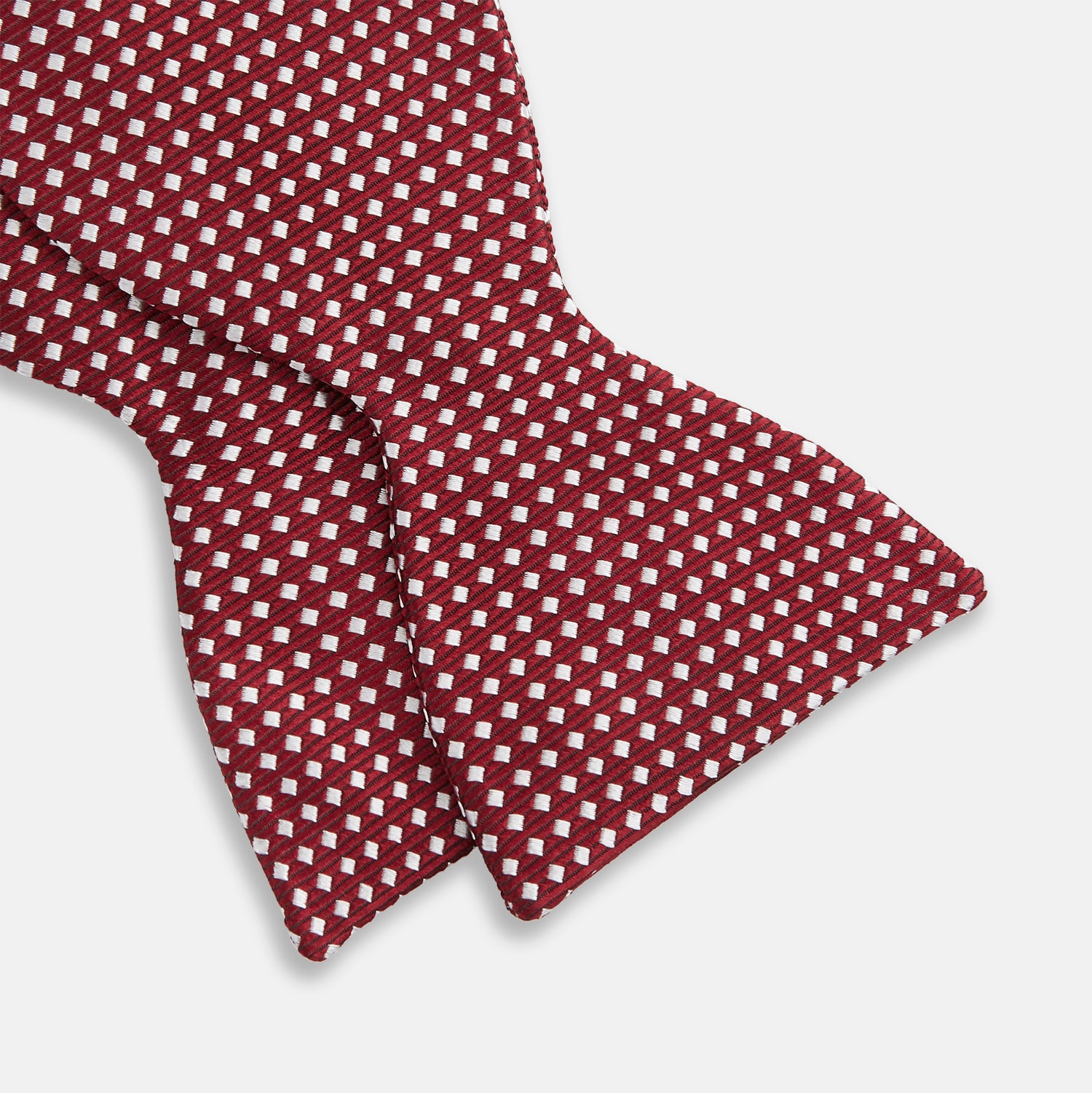 View 3 of product The Turnbull & Asser Burgundy and White Diamond Silk Bow Tie features a textured pattern of small white diamonds, ideal for white shirts, presented on a plain white background.