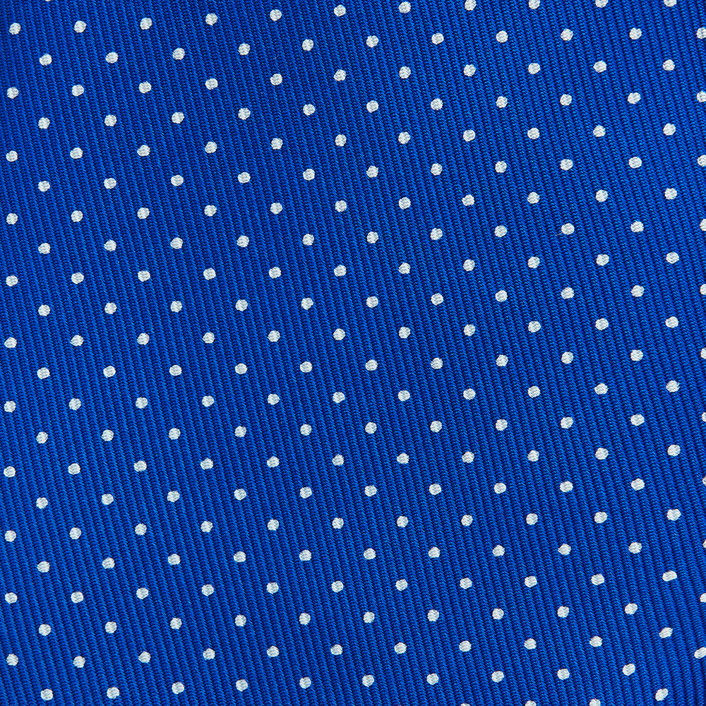 The Turnbull & Asser Long Blue and White Small Spot Printed Silk Tie, featuring white polka dots on royal blue silk, is shown rolled up on a plain white background.