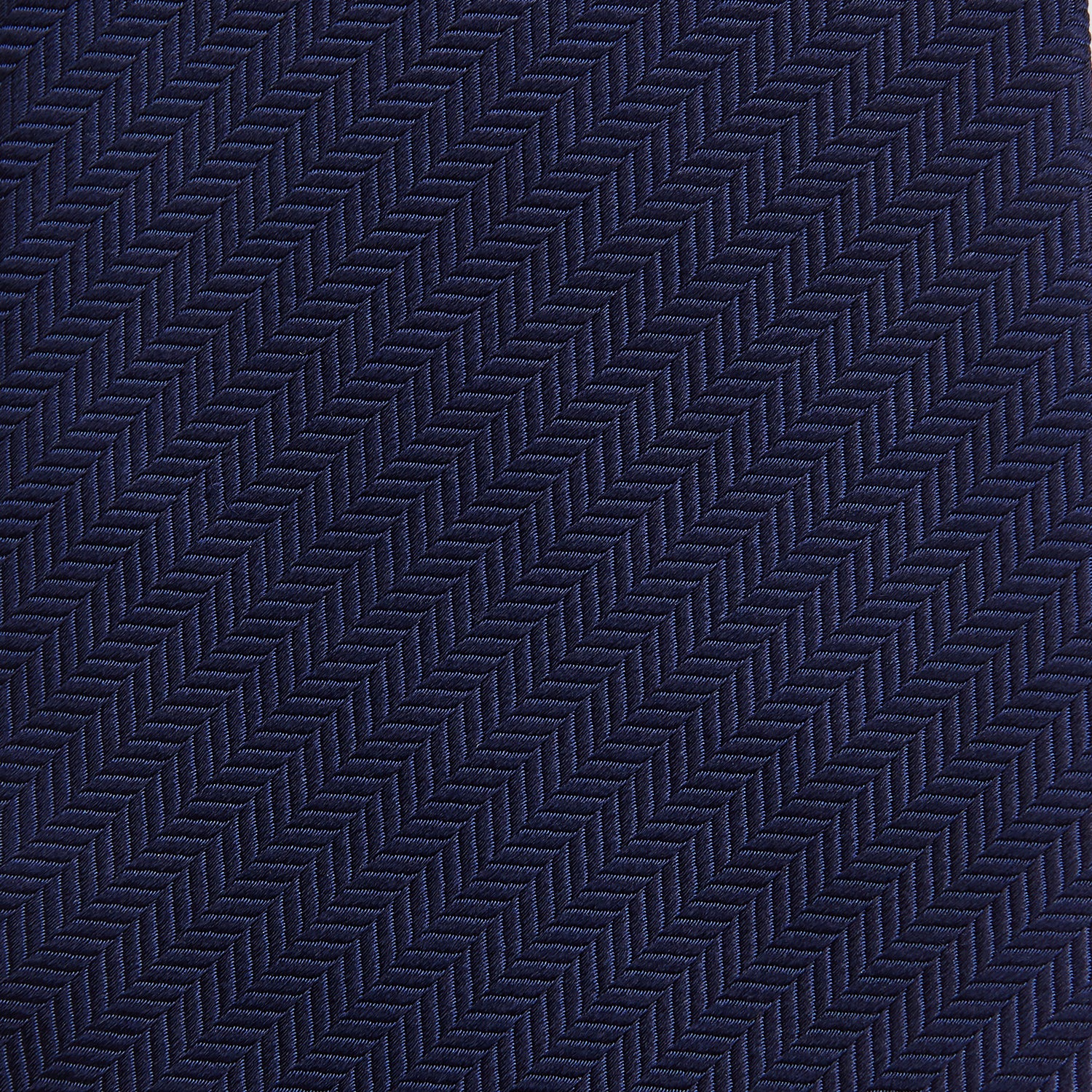 View 3 of product The Long Navy Herringbone Silk Tie by Turnbull & Asser is shown rolled up on a plain white background, highlighting its subtle herringbone weave and luxurious silk fabric.