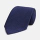 The Long Navy Herringbone Silk Tie by Turnbull & Asser is shown rolled up on a plain white background, highlighting its subtle herringbone weave and luxurious silk fabric.