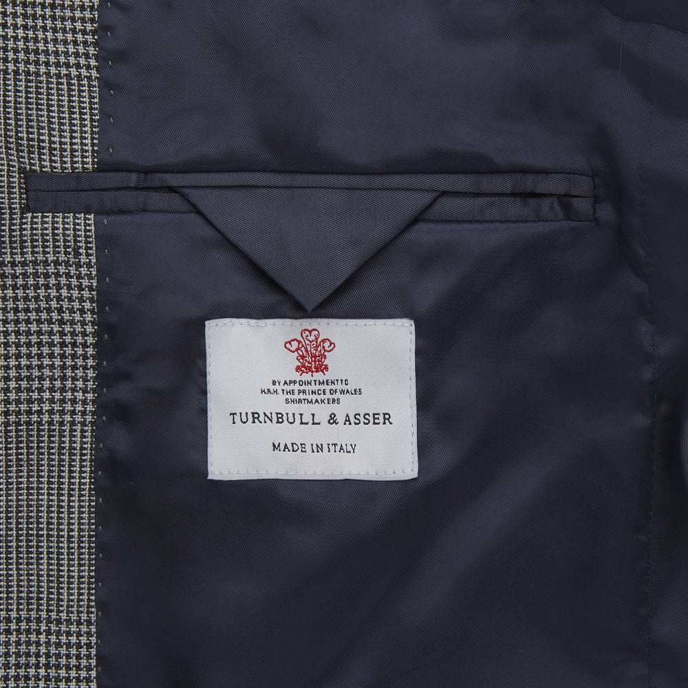 The Turnbull & Asser Grey Prince of Wales Check Wool Hopsack Jacket features a notched lapel, two-button closure, two front flap pockets, and a chest pocket, shown on a plain white background.