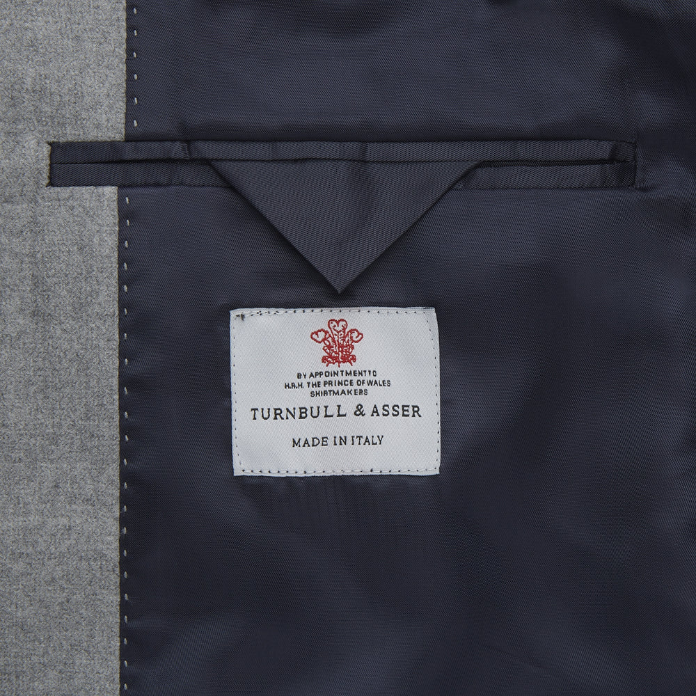 The Dove Grey Escorial Lightweight Wool Jacket by Turnbull & Asser features soft Escorial wool, a notched lapel, two front buttons, three pockets, and a single chest pocket, shown against a plain white background.
