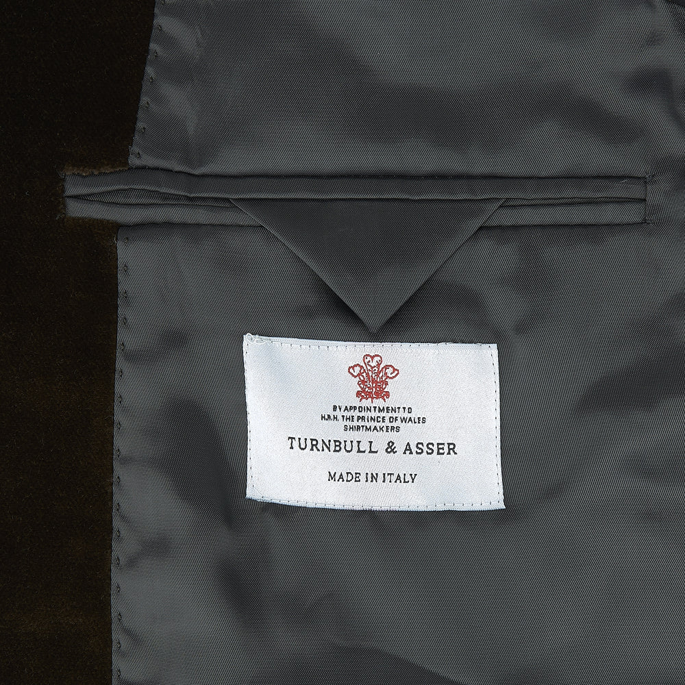 The Turnbull & Asser Brown Velvet Jacket for men features a notched lapel, two buttons, flap pockets, and a chest pocket, shown against a plain white background.