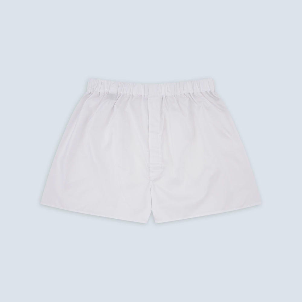 Turnbull & Asser White Sea Island Quality Cotton Twill Boxer Shorts feature an elastic waistband and are photographed laid flat on a light blue background for a luxurious touch.
