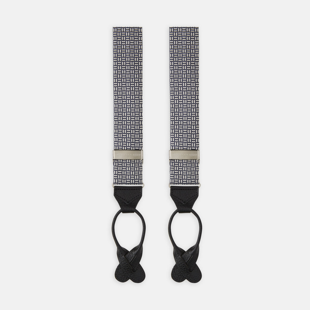 Turnbull & Asser’s Silver and Charcoal Geometric Adjustable Silk Braces feature a black and white geometric pattern, black leather looped ends, and metal hardware, echoing classic refinement against a plain white background.