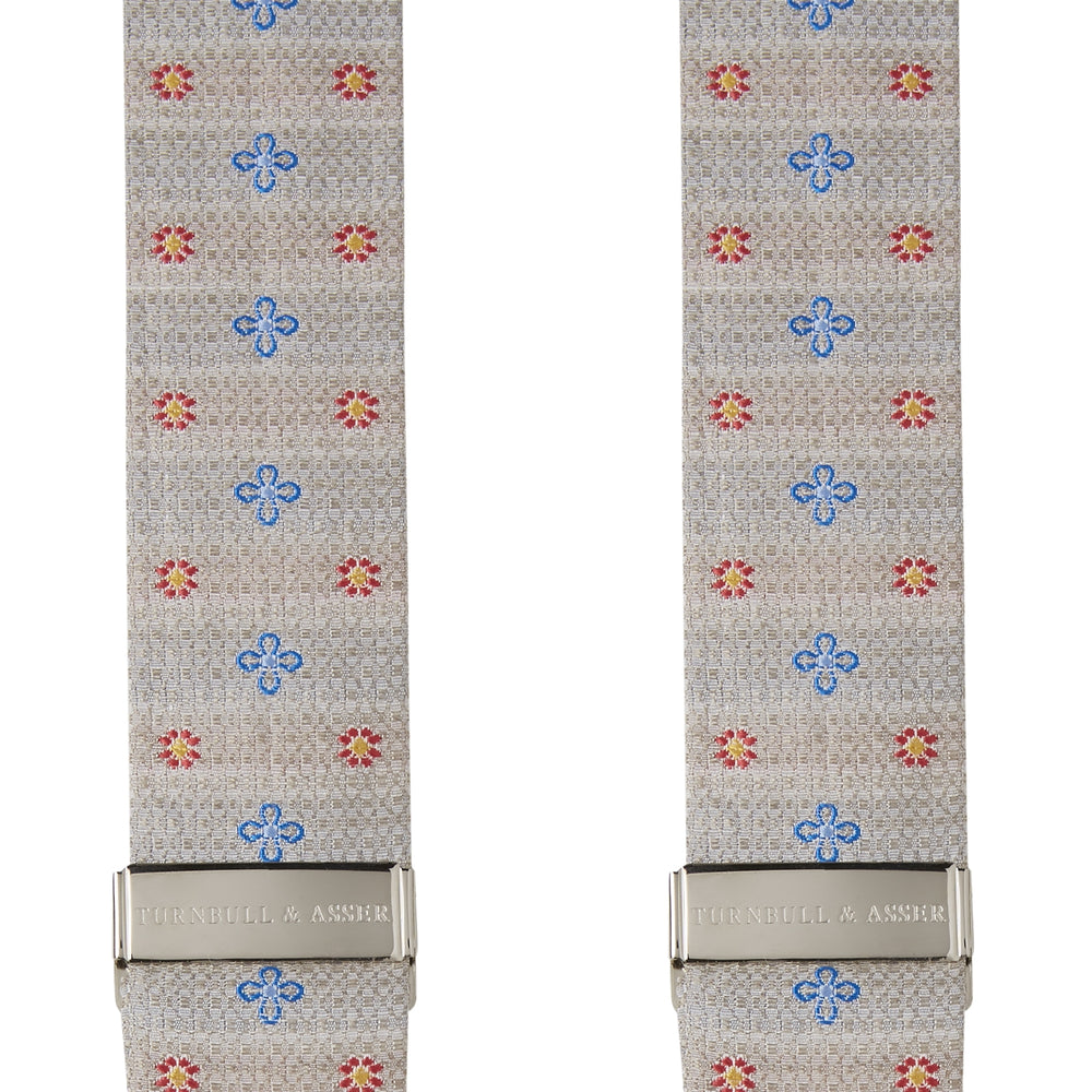 Turnbull & Asser’s Dove Grey Floral Silk and Linen Adjustable Braces feature blue and red flowers, black leather ends, and silver adjusters—an elegant choice to add flair to your summer suit.