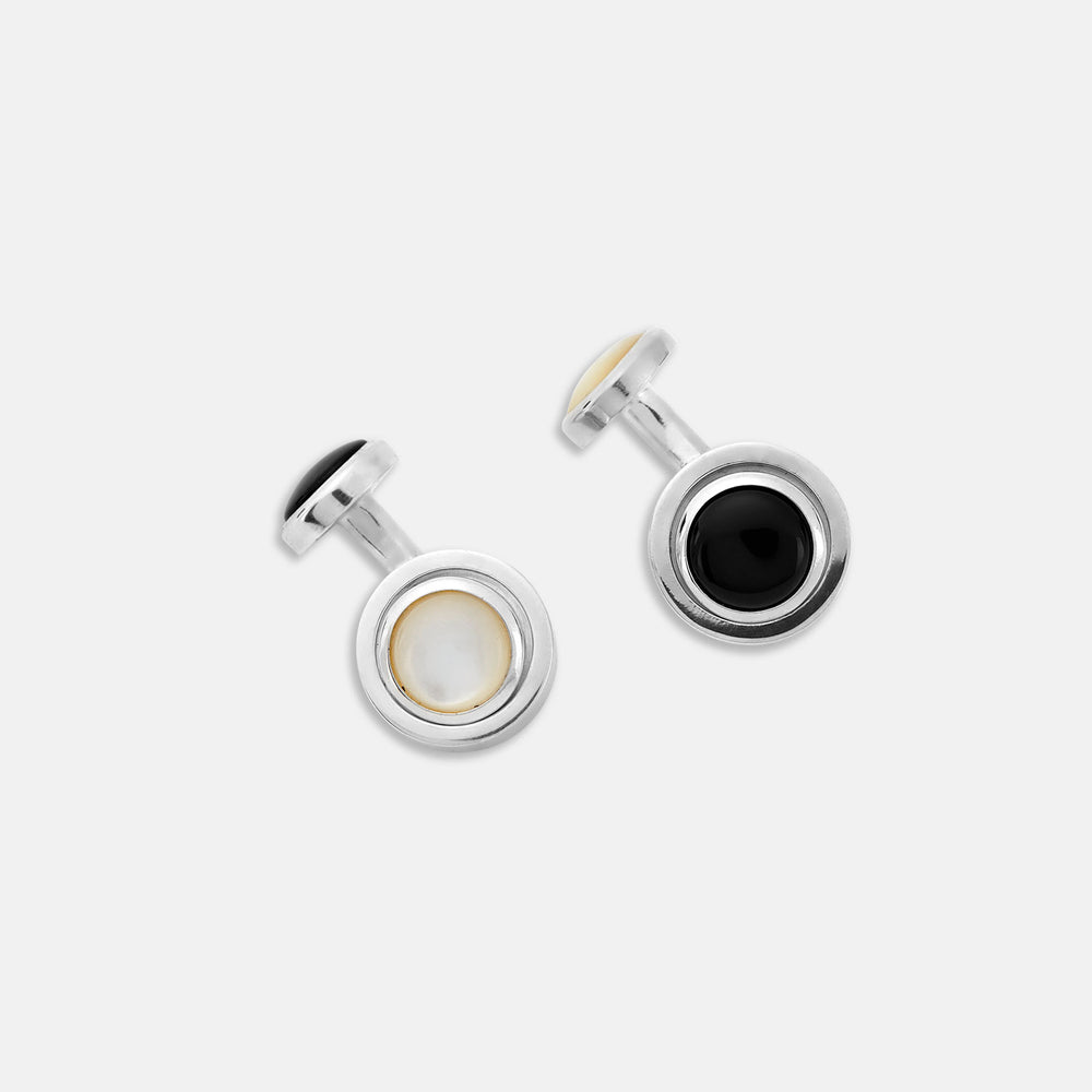 Turnbull & Asser’s Reversible Monochrome Sterling Silver Round Cufflinks feature elegant edges with one white mother-of-pearl center and the other a black onyx center, shown on a plain light gray background.