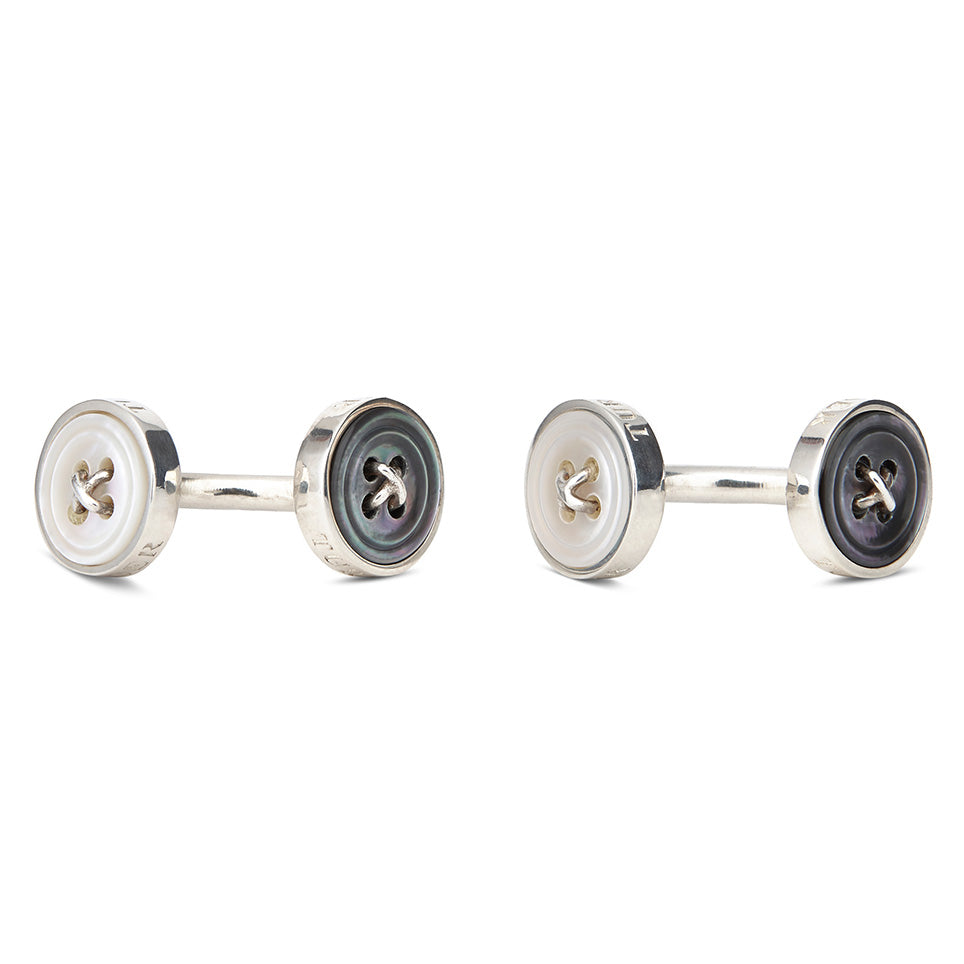 Turnbull & Asser’s Reversible Sterling Silver Mother-of-Pearl Button Cufflinks feature a round button design with four central holes, showcasing a dark iridescent face on one side and a light mother-of-pearl face on the other.