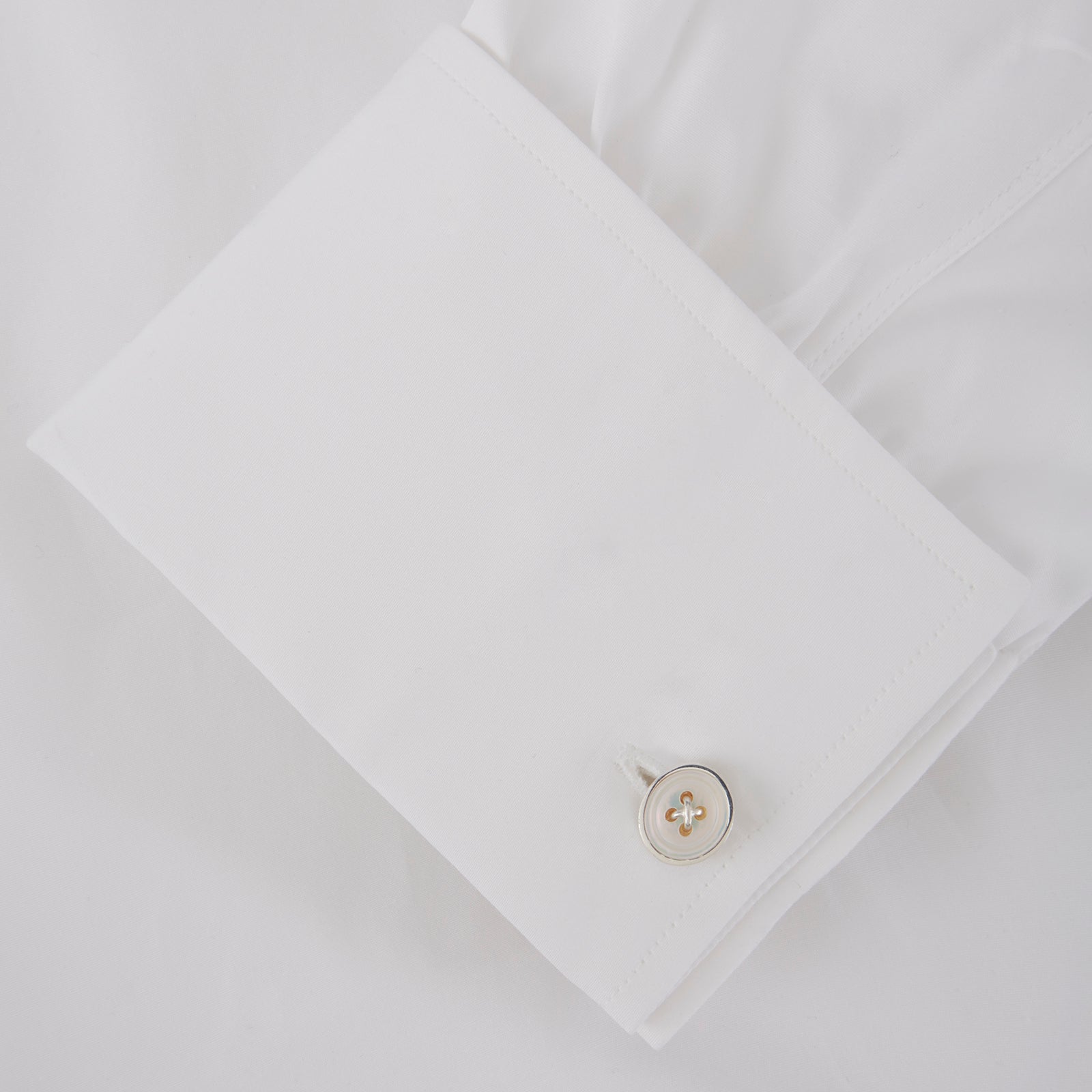 View 2 of product Turnbull & Asser’s Reversible Sterling Silver Mother-of-Pearl Button Cufflinks feature a round button design with four central holes, showcasing a dark iridescent face on one side and a light mother-of-pearl face on the other.