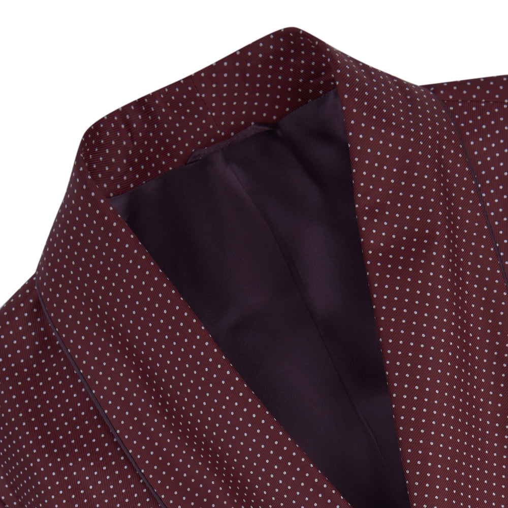The Turnbull & Asser Burgundy Piped Silk Spot Gown features small white polka dots, a shawl collar, fabric belt, and chest pocket—luxurious nightwear and a stylish men’s statement piece—shown on a white background.