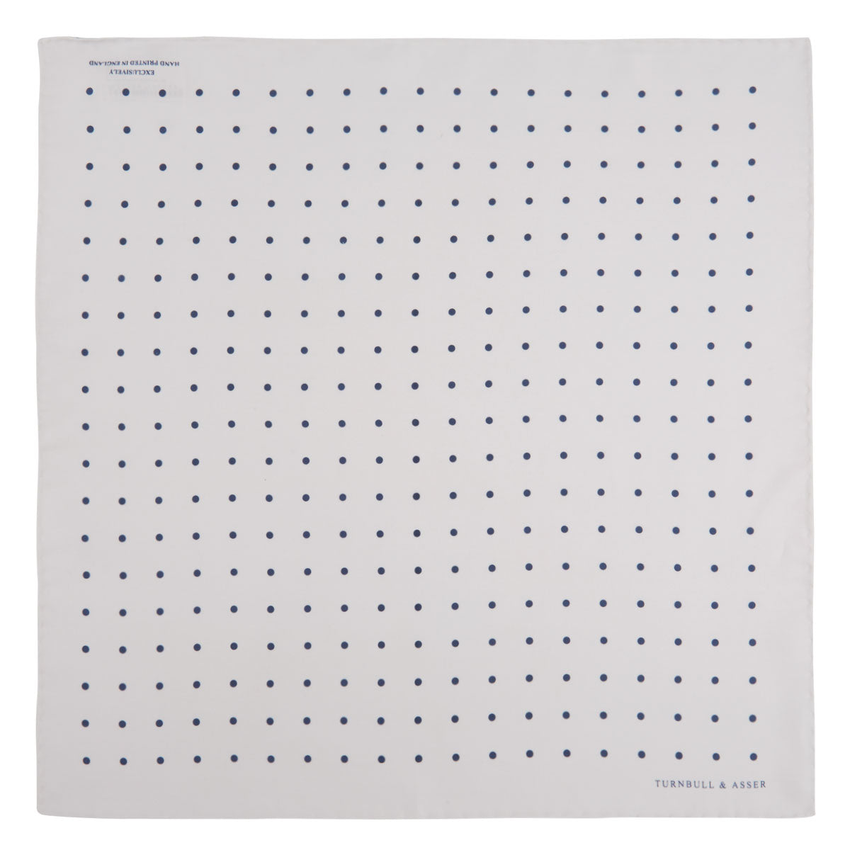 View 2 of product The White and Navy Spot Silk Pocket Square by Turnbull & Asser features evenly spaced blue dots and the brand's logo in blue on the bottom right, with a folded corner highlighting this classic men's accessory.