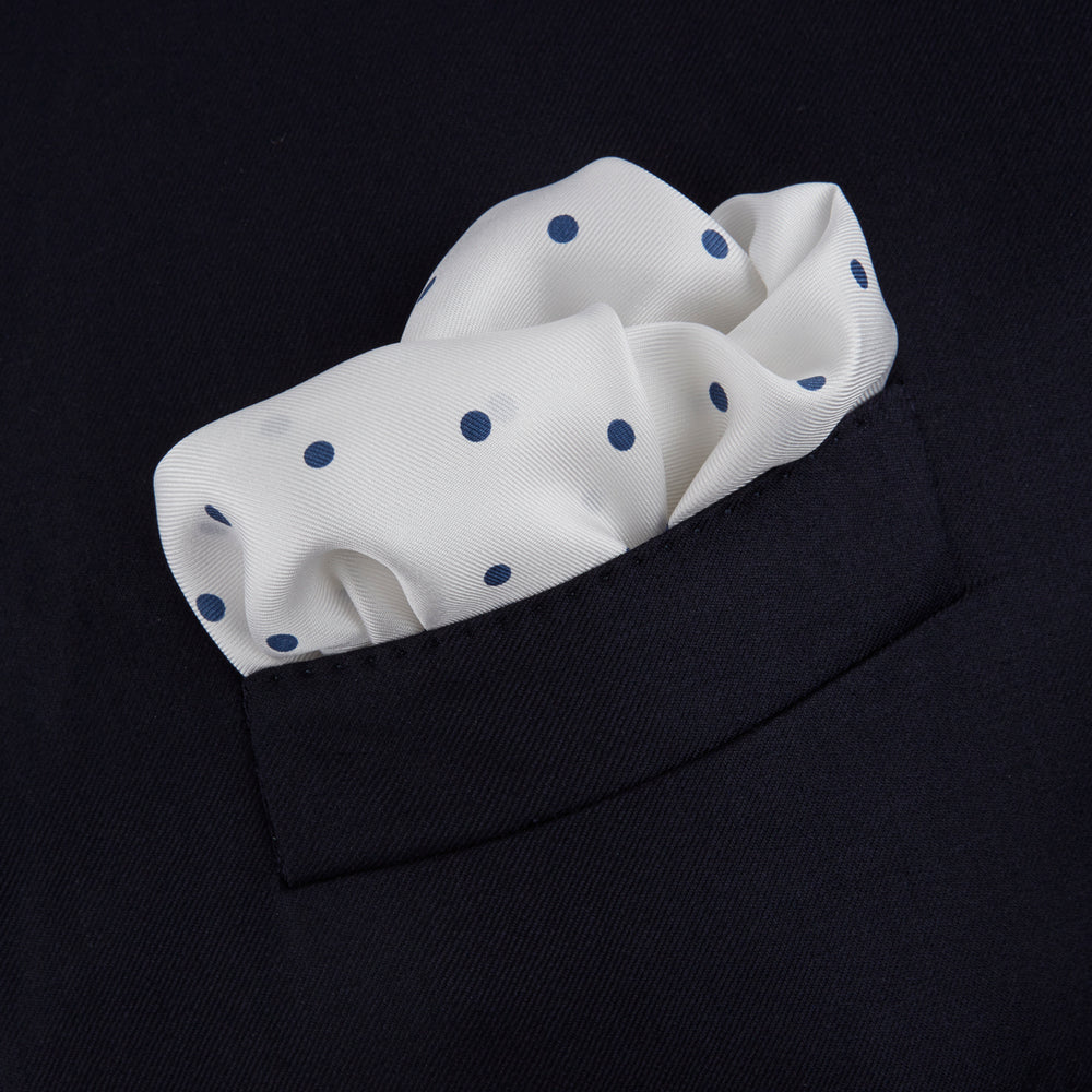 The White and Navy Spot Silk Pocket Square by Turnbull & Asser features evenly spaced blue dots and the brand's logo in blue on the bottom right, with a folded corner highlighting this classic men's accessory.