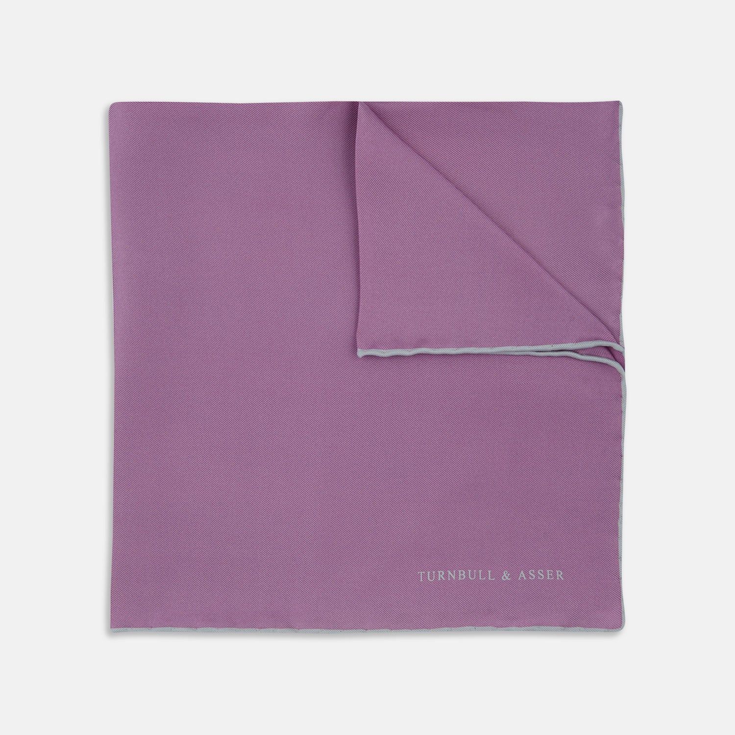 View 1 of product The Lilac and White Piped Silk Pocket Square by Turnbull & Asser features a smooth lilac silk fabric with a refined white piped edge and the brand's signature printed in white on the lower right corner.