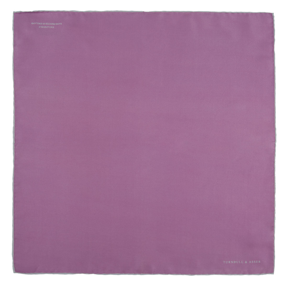 View 2 of product The Lilac and White Piped Silk Pocket Square by Turnbull & Asser features a smooth lilac silk fabric with a refined white piped edge and the brand's signature printed in white on the lower right corner.