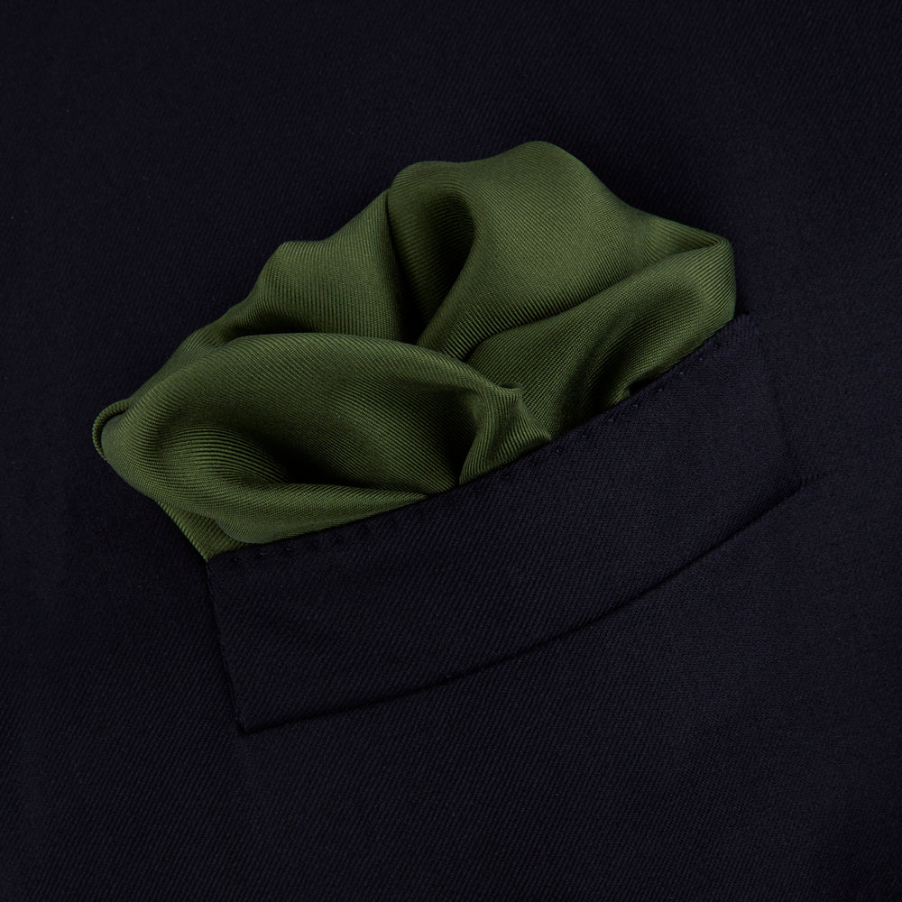 The Olive and White Piped Silk Pocket Square by Turnbull & Asser features a subtle white border and the brand’s embroidered logo—a timeless accessory for any occasion.