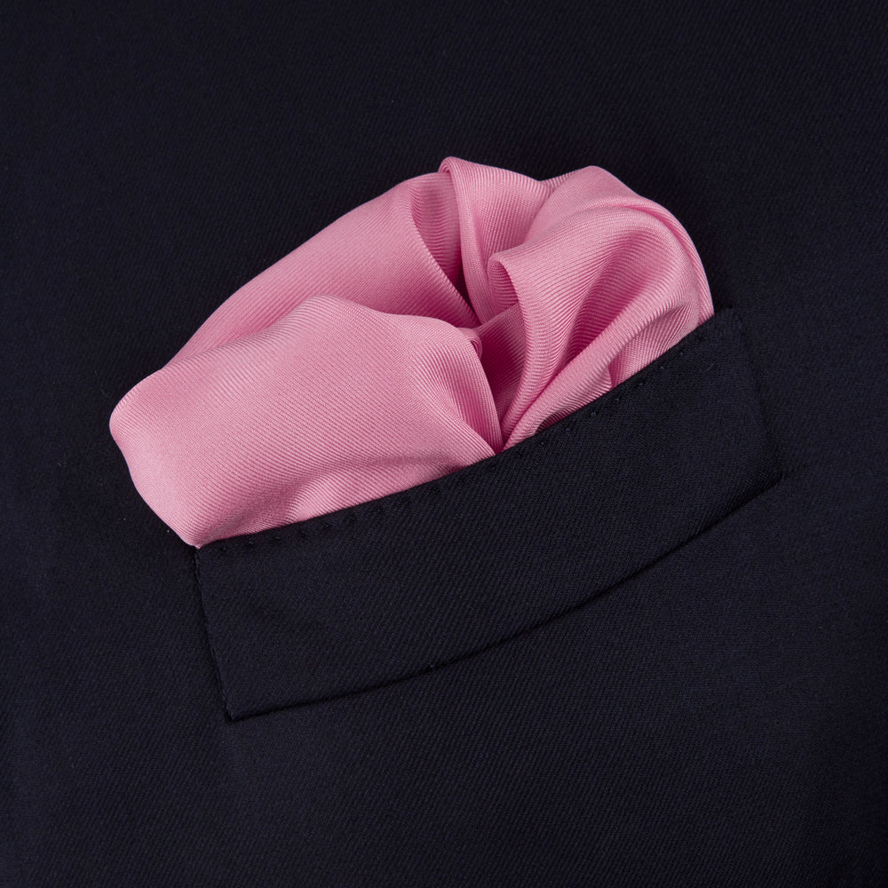 The Rose and Navy Piped Silk Pocket Square by Turnbull & Asser features classic pink silk with navy edging, neatly folded to display both sides. Turnbull & Asser’s logo appears in white on the lower right corner for a refined finish.