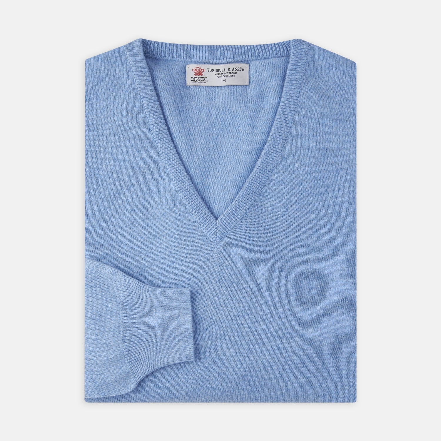 View 1 of product A Sky Blue Fine Cashmere V-Neck Jumper by Turnbull & Asser, neatly folded with visible ribbed collar and cuff, is displayed on a white background. The label appears inside the collar.