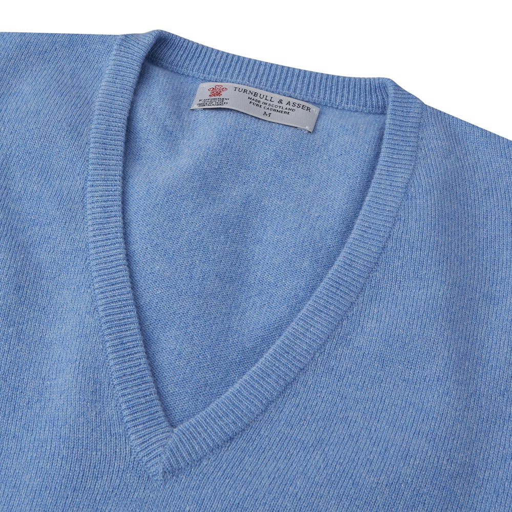 The Sky Blue Fine Cashmere Slipover by Turnbull & Asser is laid flat on a white background, showcasing its lightweight design and ribbed neckline, armholes, and hem for a refined finish.