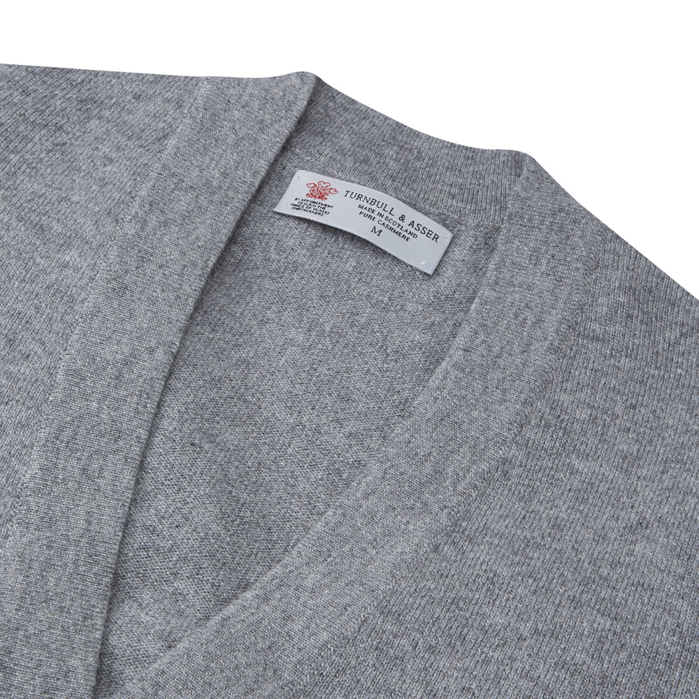 The Grey Fine Cashmere Cardigan by Turnbull & Asser is a long-sleeve, button-up sweater with two front pockets, shown on a white background.