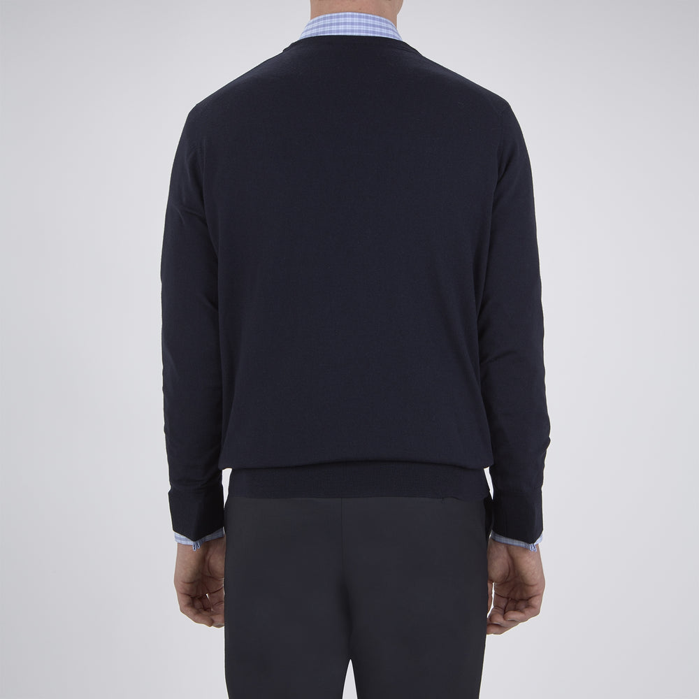 The Turnbull & Asser Indigo V-Neck Merino Wool Jumper, shown neatly folded with ribbed cuffs and a visible inner label, is a timeless essential in versatile navy, perfect for any gentleman’s wardrobe.