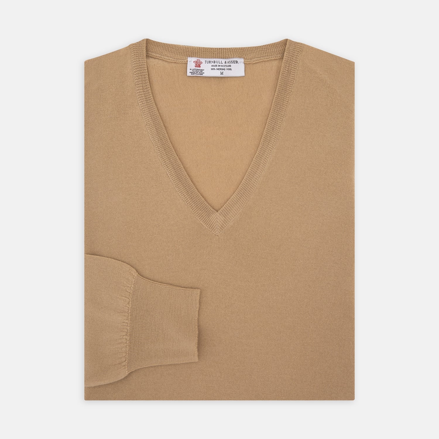 View 1 of product The Turnbull & Asser Camel V-Neck Merino Wool Jumper, with ribbed cuffs and a visible white neckline label, is neatly folded with one sleeve showing—an essential, versatile staple for any gentleman's wardrobe.