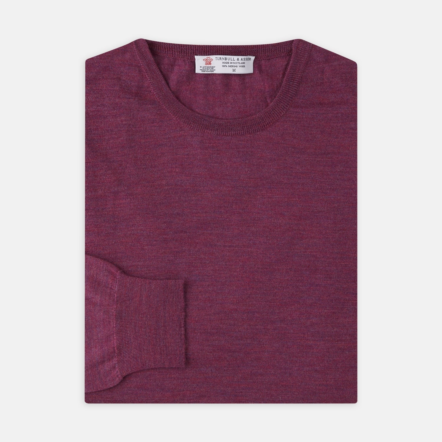 View 1 of product The Plum Fine Merino Crew Neck Jumper by Turnbull & Asser features classic Scottish knitwear craftsmanship in a rich maroon shade, shown neatly folded with long sleeves against a plain white background.