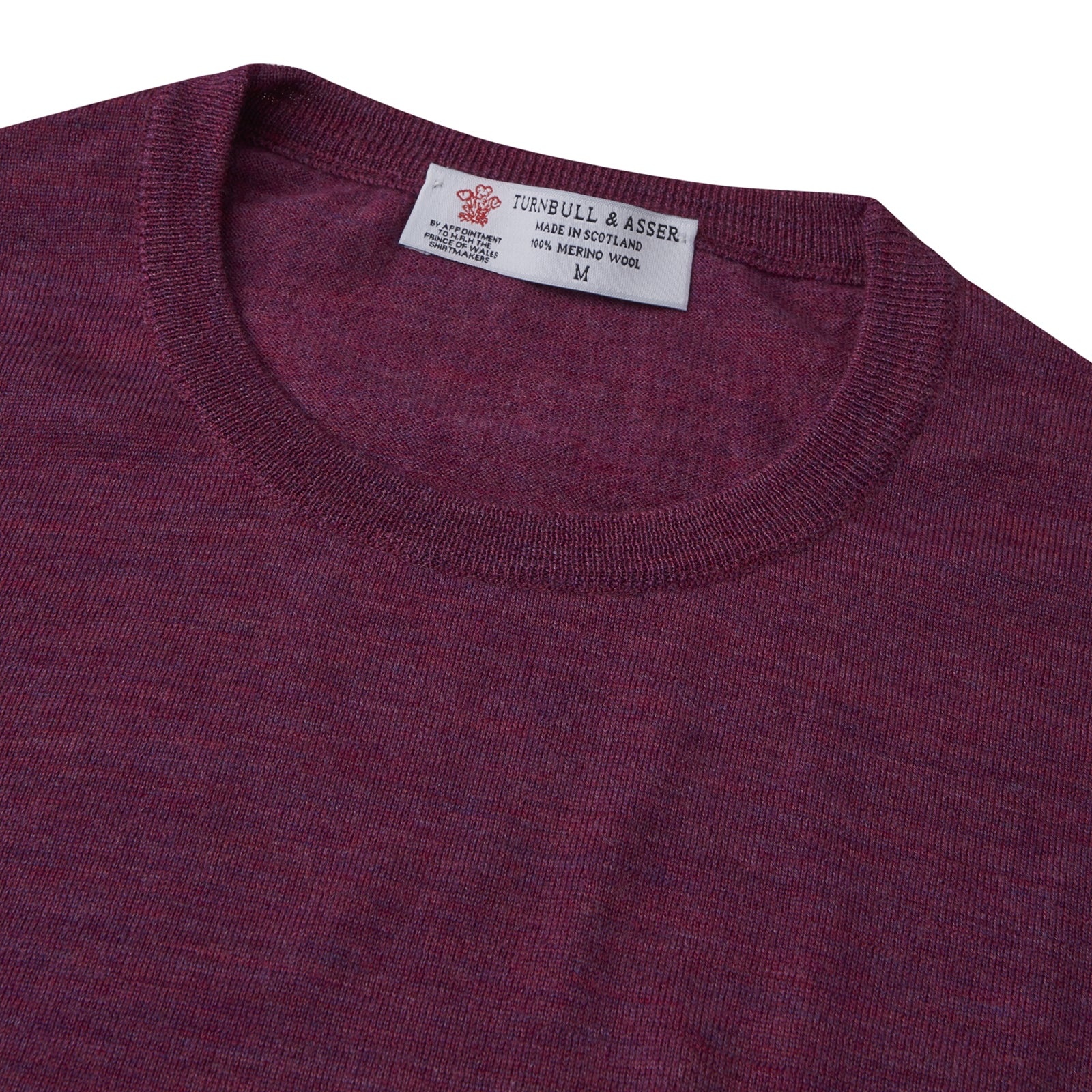View 2 of product The Plum Fine Merino Crew Neck Jumper by Turnbull & Asser features classic Scottish knitwear craftsmanship in a rich maroon shade, shown neatly folded with long sleeves against a plain white background.