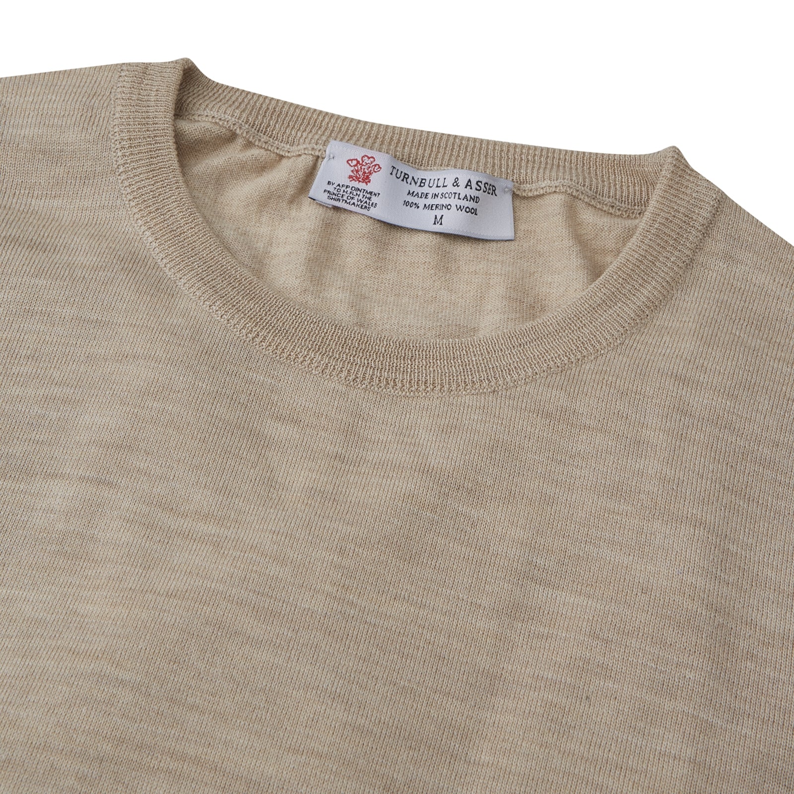 View 2 of product The Camel Fine Merino Crewneck Jumper by Turnbull & Asser is a light brown Scottish knitwear piece with a ribbed collar and cuffs, neatly displayed on a plain white background.
