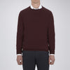 View 2 of product The Turnbull & Asser Wine Crew Neck Merino Wool Jumper, featuring ribbed cuffs and a classic design, is neatly folded on a white background.