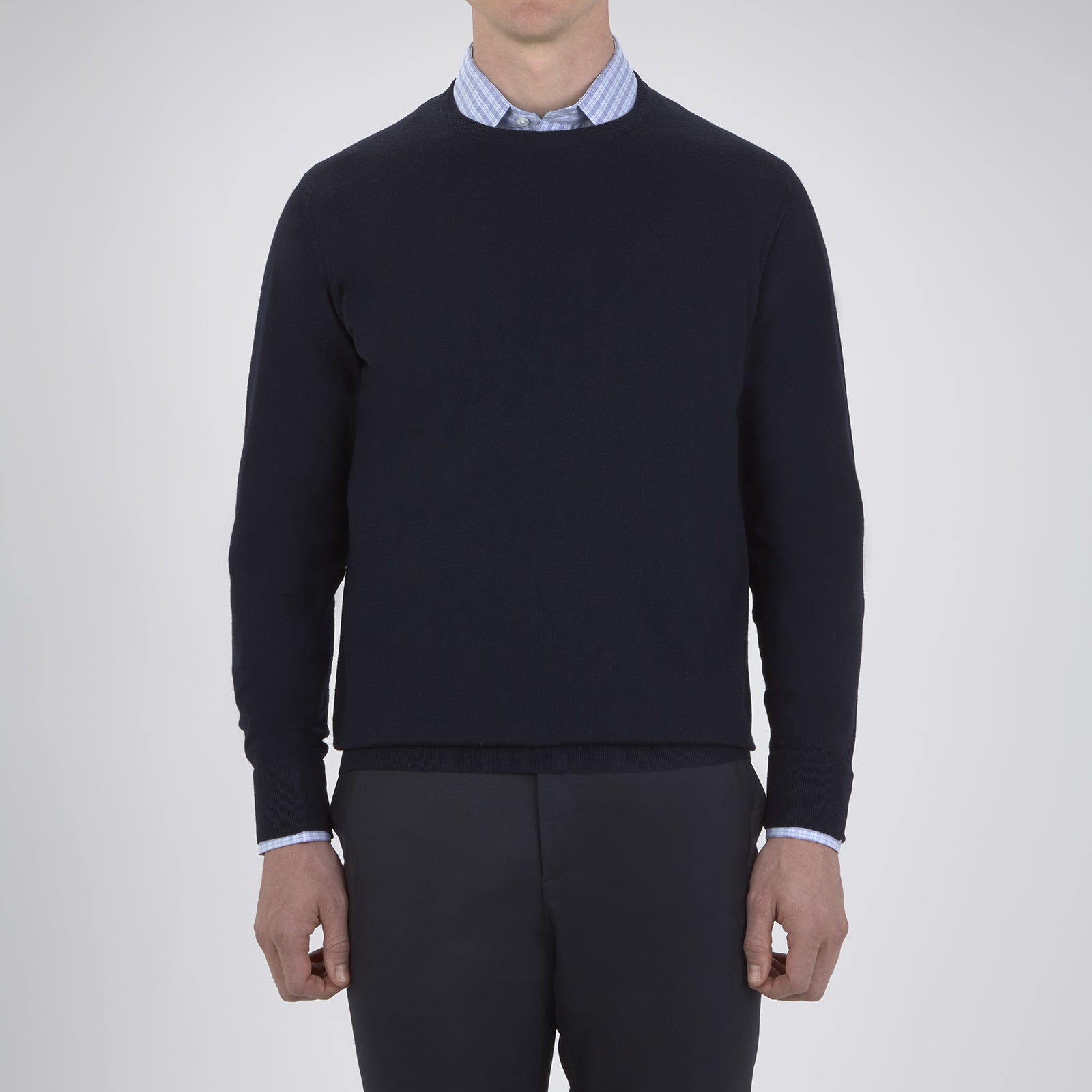 View 2 of product A neatly folded Indigo Crew Neck Merino Wool Jumper by Turnbull & Asser, featuring a visible brand label at the collar and one sleeve tucked across the front, displayed on a white background—a versatile staple for any gentleman's wardrobe.