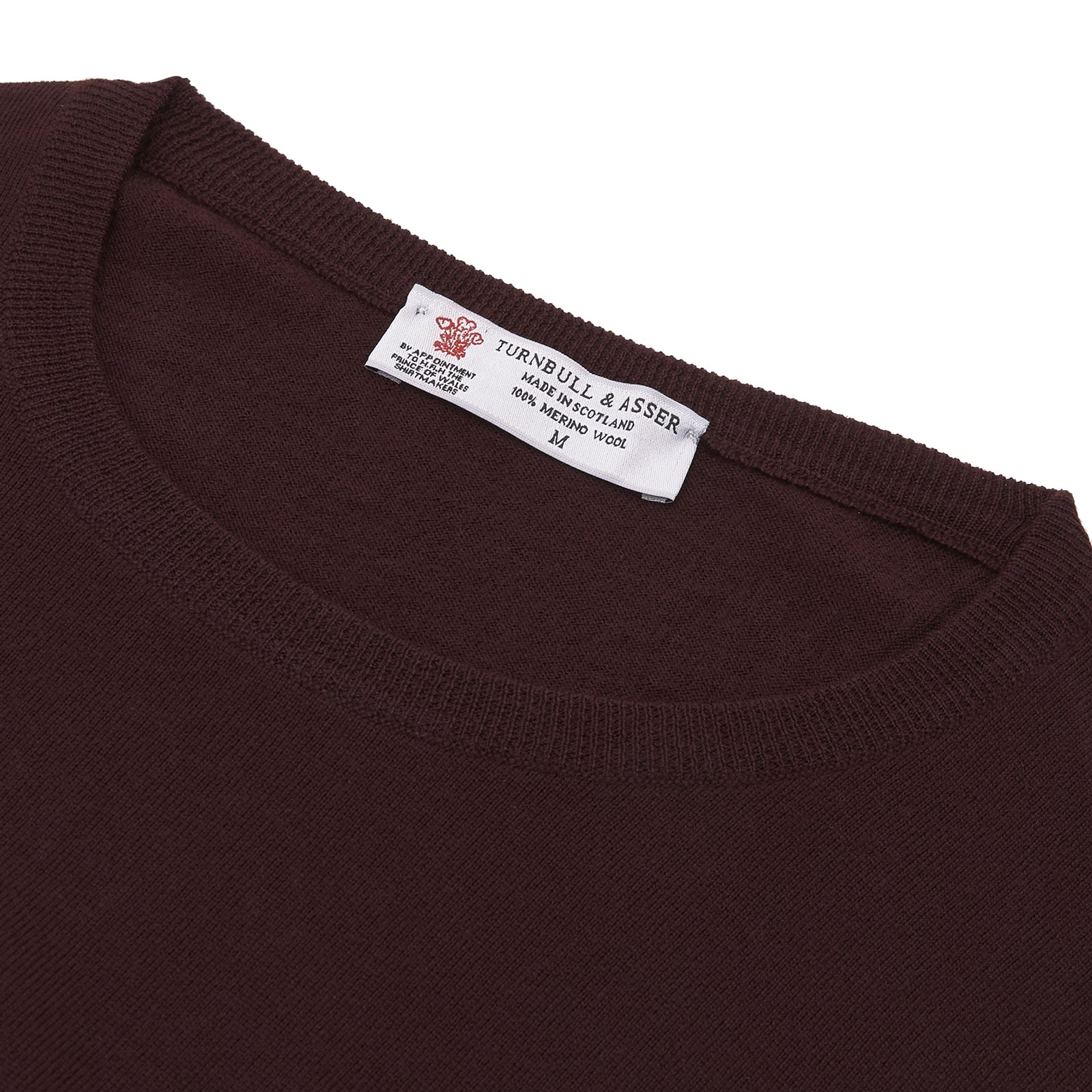 View 4 of product The Turnbull & Asser Wine Crew Neck Merino Wool Jumper, featuring ribbed cuffs and a classic design, is neatly folded on a white background.
