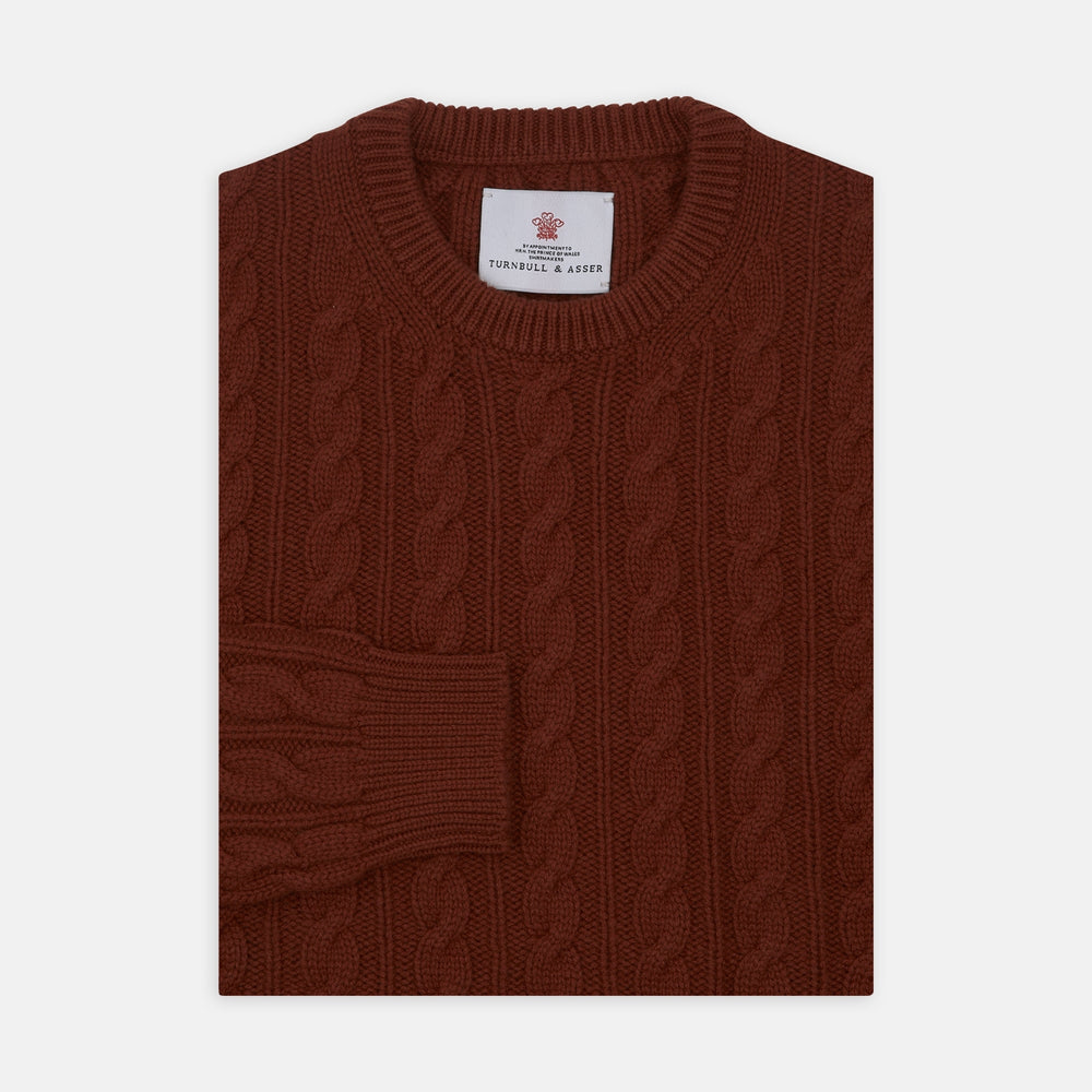 The Harissa Crew Neck Cable Knit Cashmere Jumper by Turnbull & Asser features a chunky, folded cable knit in deep harissa, with ribbed crew neckline and cuffs, and a signature label on the inside collar.