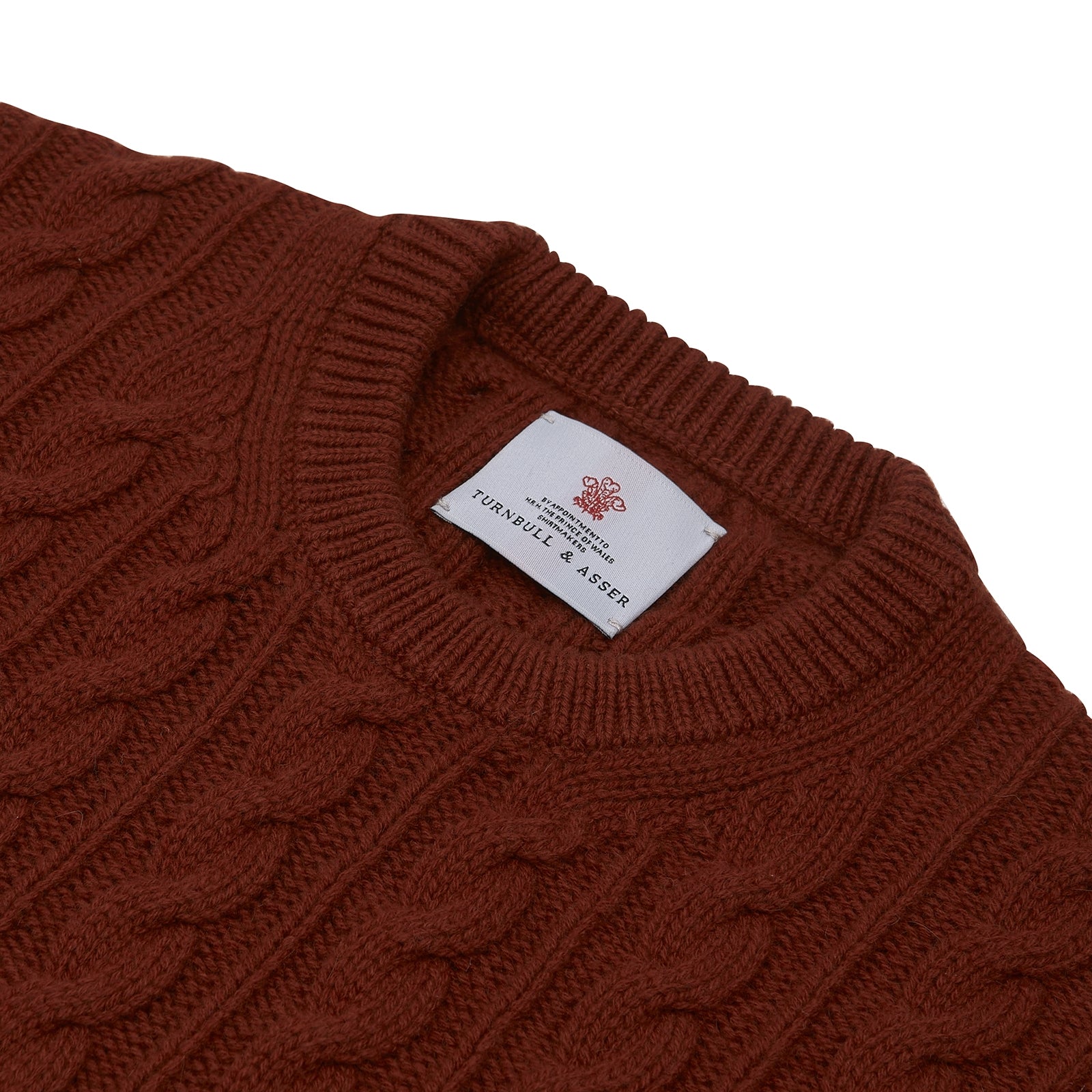 View 4 of product The Harissa Crew Neck Cable Knit Cashmere Jumper by Turnbull & Asser features a chunky, folded cable knit in deep harissa, with ribbed crew neckline and cuffs, and a signature label on the inside collar.