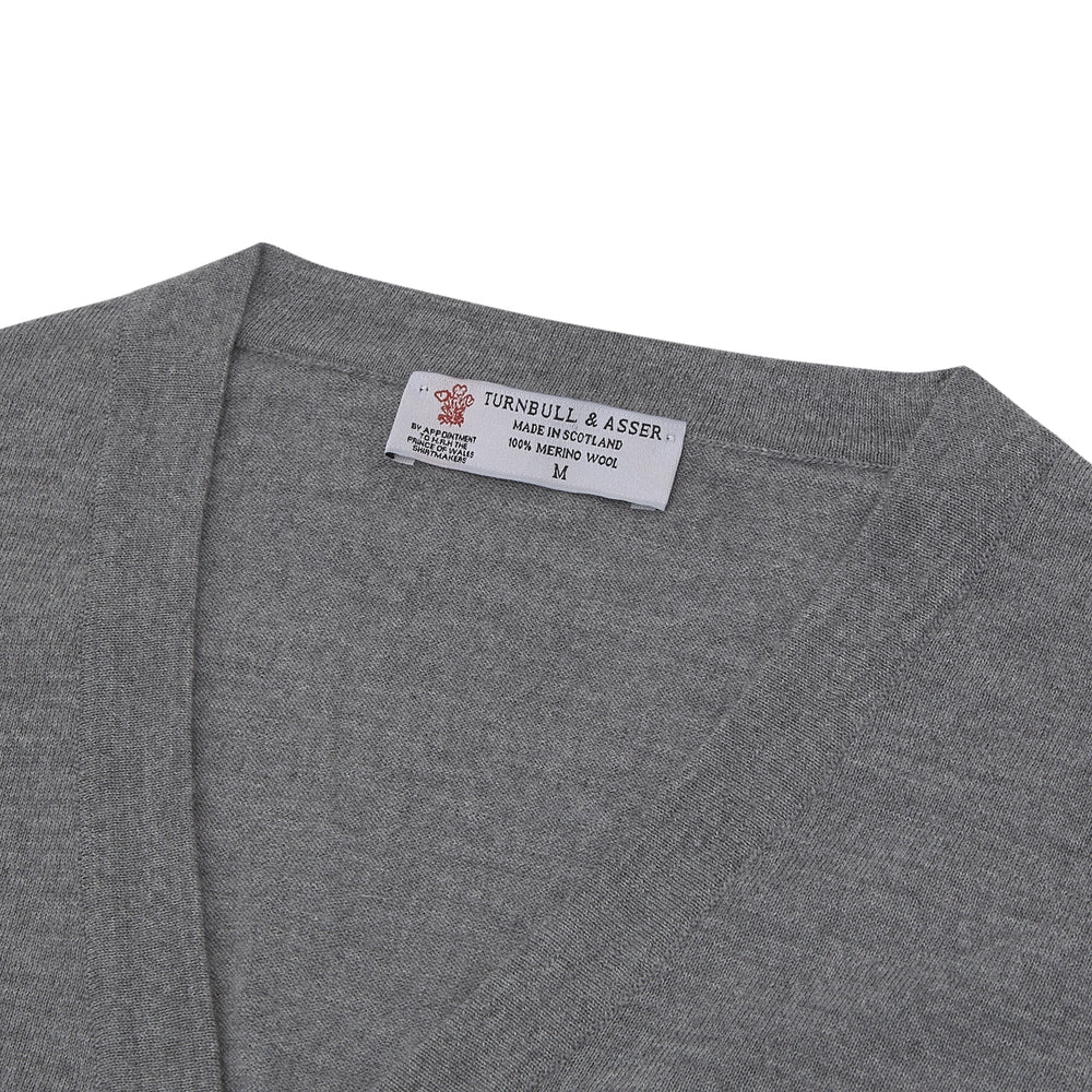 The Flannel Grey Merino Wool Cardigan by Turnbull & Asser features a light grey flannel finish, V-neck, ribbed cuffs, and button-up front—crafted for timeless style and comfort.