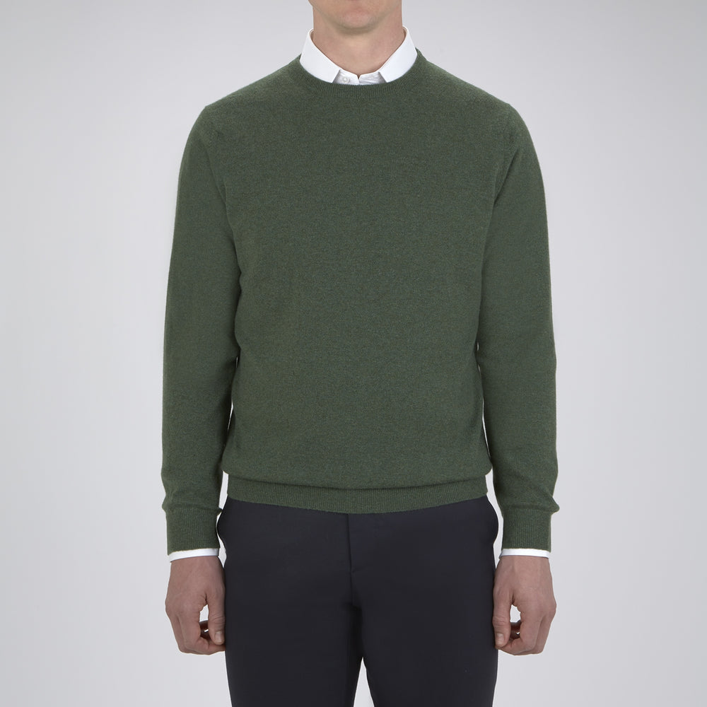 The Turnbull & Asser Green Crew Neck Cashmere Jumper, crafted from luxurious Scottish cashmere with ribbed cuffs, is neatly folded and displayed on a plain white background with the brand label visible inside the neckline.