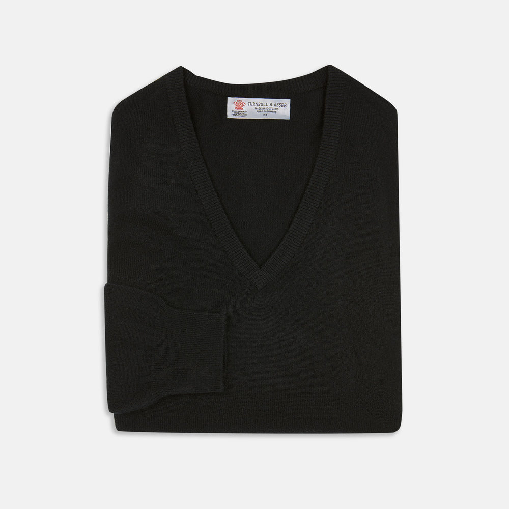 The Turnbull & Asser Black V-Neck Cashmere Jumper is neatly folded, crafted from luxury Scottish cashmere, and features a visible brand label inside the collar, displayed on a plain white background.