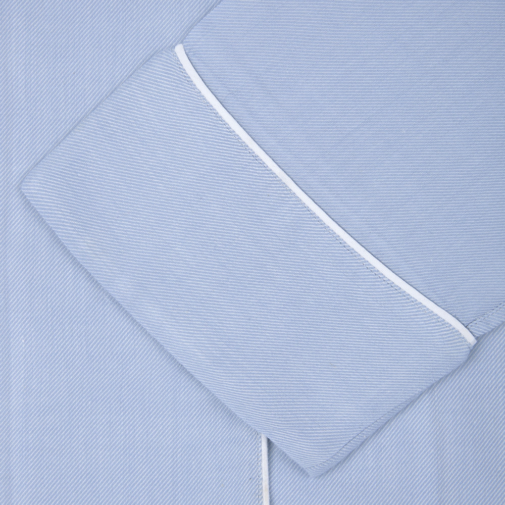Turnbull & Asser Ladies' Blue Cotton-Cashmere Pyjama Set with white piping features a collared button-up top, neatly folded, and matching drawstring pants laid flat on a plain white background.