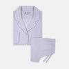 View 1 of product The Ladies' Lilac Cotton-Cashmere Pyjama Set by Turnbull & Asser, with purple piping, collared button-up top featuring a chest pocket, and matching drawstring bottoms, is folded and displayed on a white background.